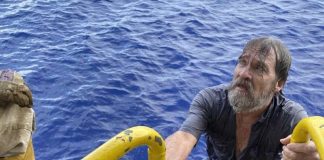 Ta rescata un marinero bibo haya ta flota riba un pida di su boto cu a sink riba lama