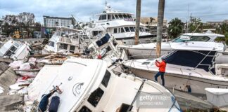 Un homber sacando potret di botonan destrui pa horcan Ian na Fort Meyers.