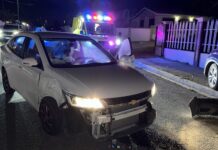 Dama na stuur di un auto Chevrolet a hala na su man drechi y a dal contra un Ford Lincoln staciona